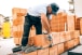 industrial worker building exterior walls, using hammer for laying bricks in cement  Detail of worker with tools and concrete